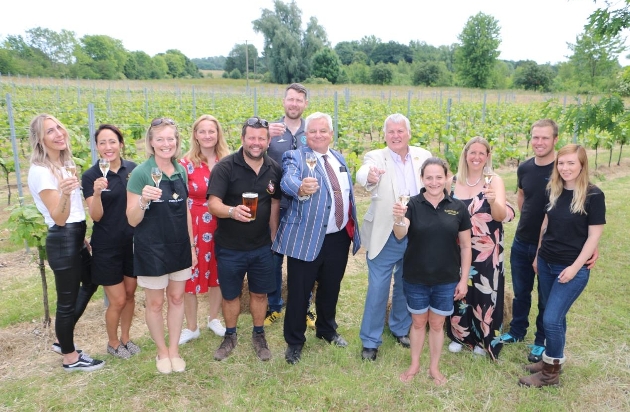 group of people standing in a vineyard raising a toast to drink