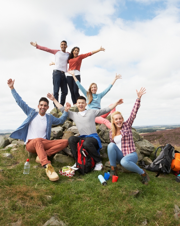 group of friends cheering they have reached the top of a cliff