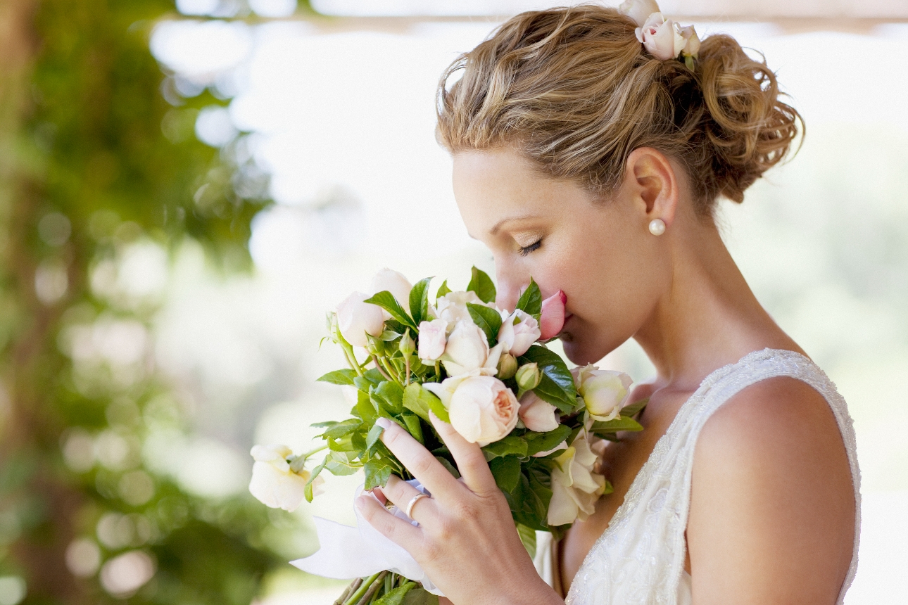 woman in wedding dress smelling wedding bouquet of flowers