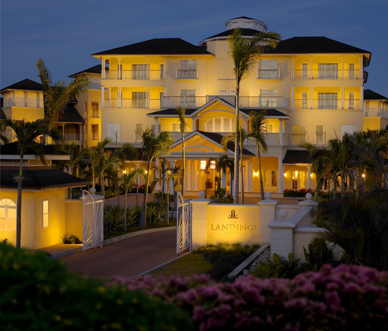 exterior of white hotel at night with trees and uplighting