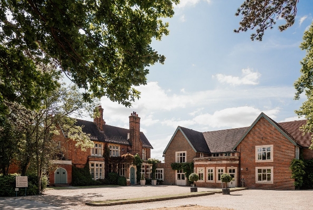 country house with drive way, ivy on the walls, and large trees