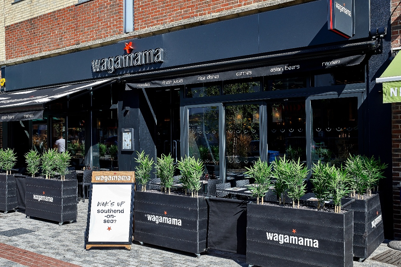 wagamama restaurant front, black sign with tables outside 