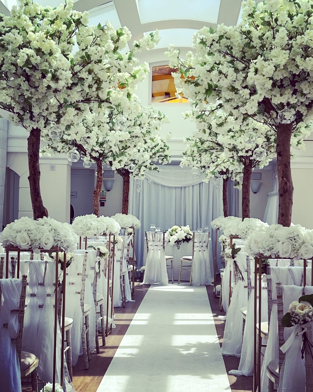 white blossom trees and floral pew ends lining an aisle