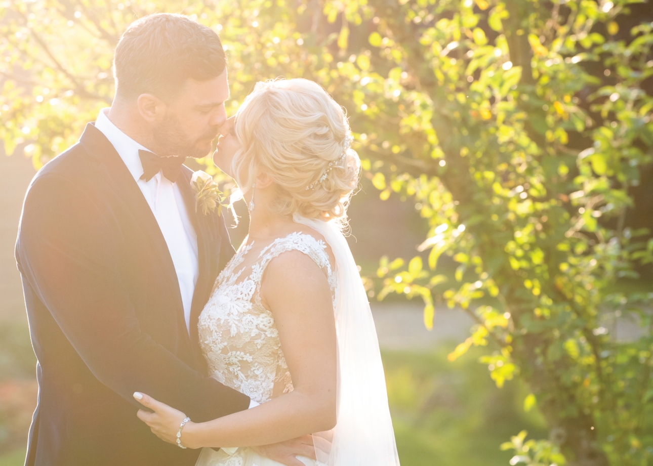 bride and groom kissing in the sunlight