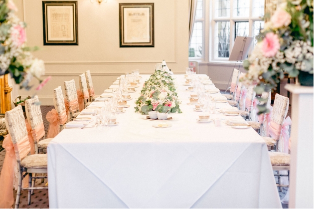 wedding table set up in a long trestle table style with white cloth and table settings