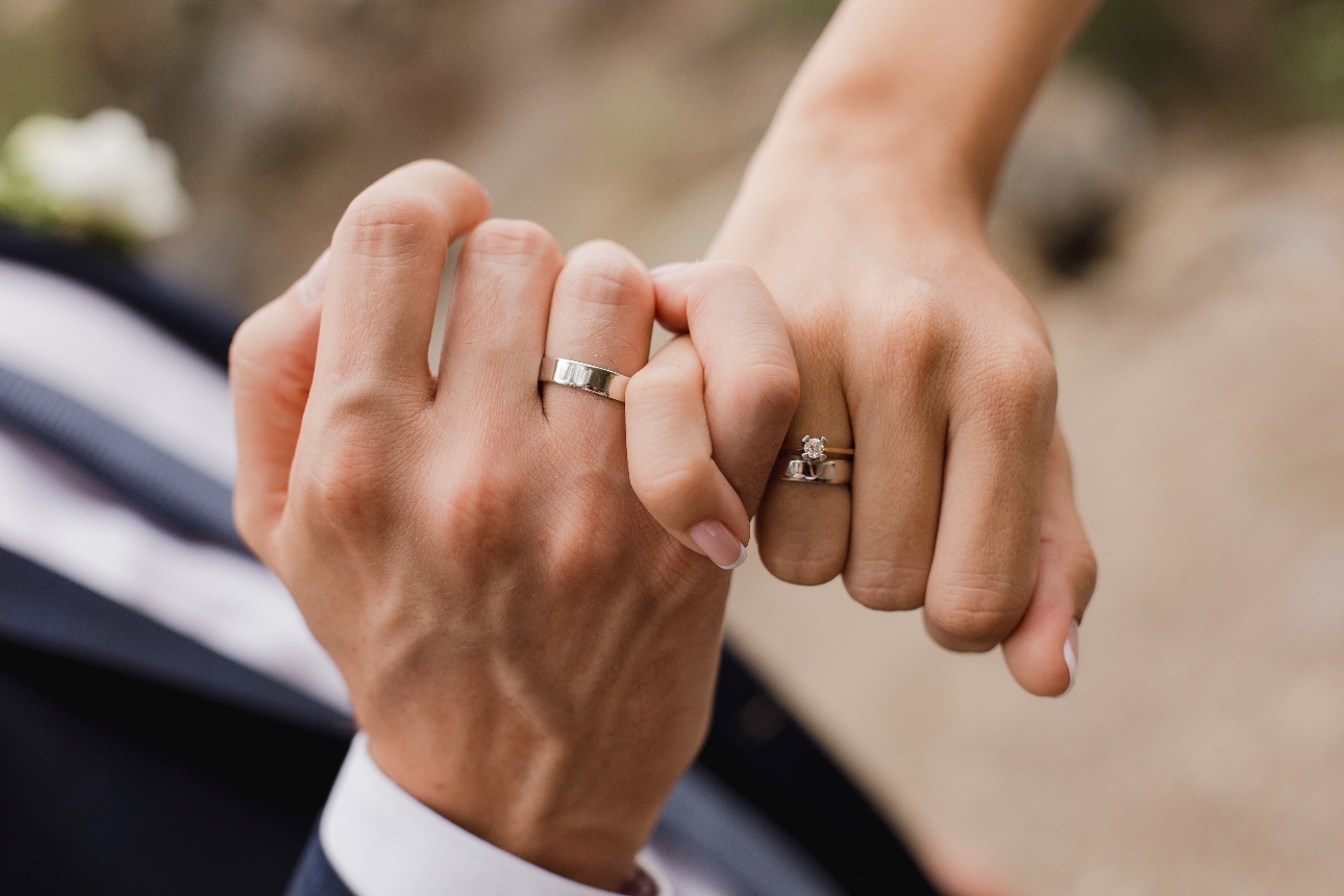 two hand held together by their litte finger showing wedding bands
