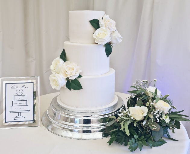 cake on table white with green flowers and bouquet on table