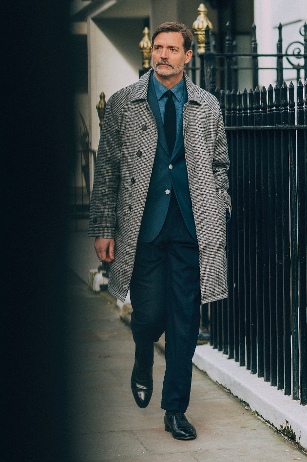 Man walking down the street wearing a suit and grey coat