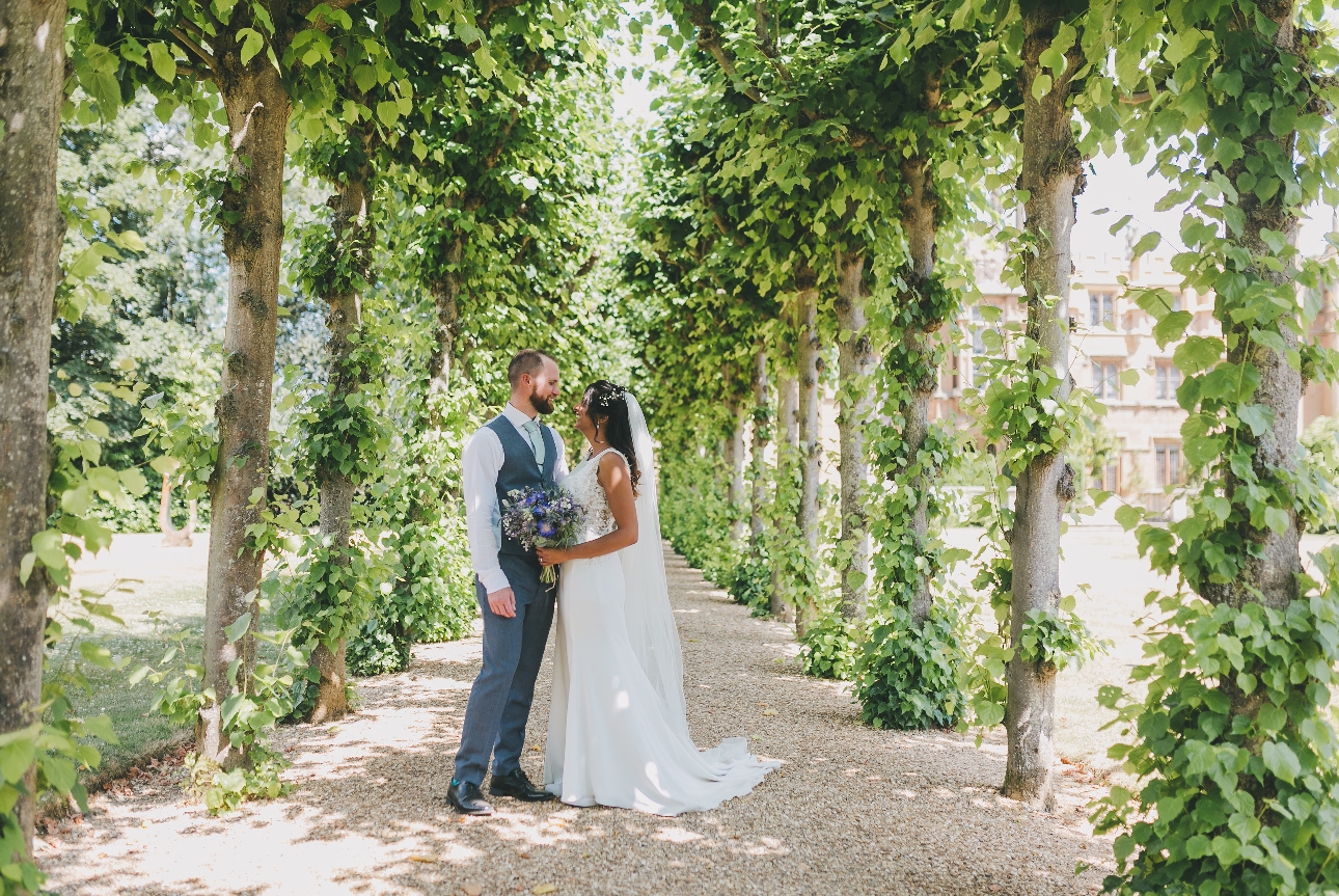 couple standing in avenue of trees in grounds of their venue