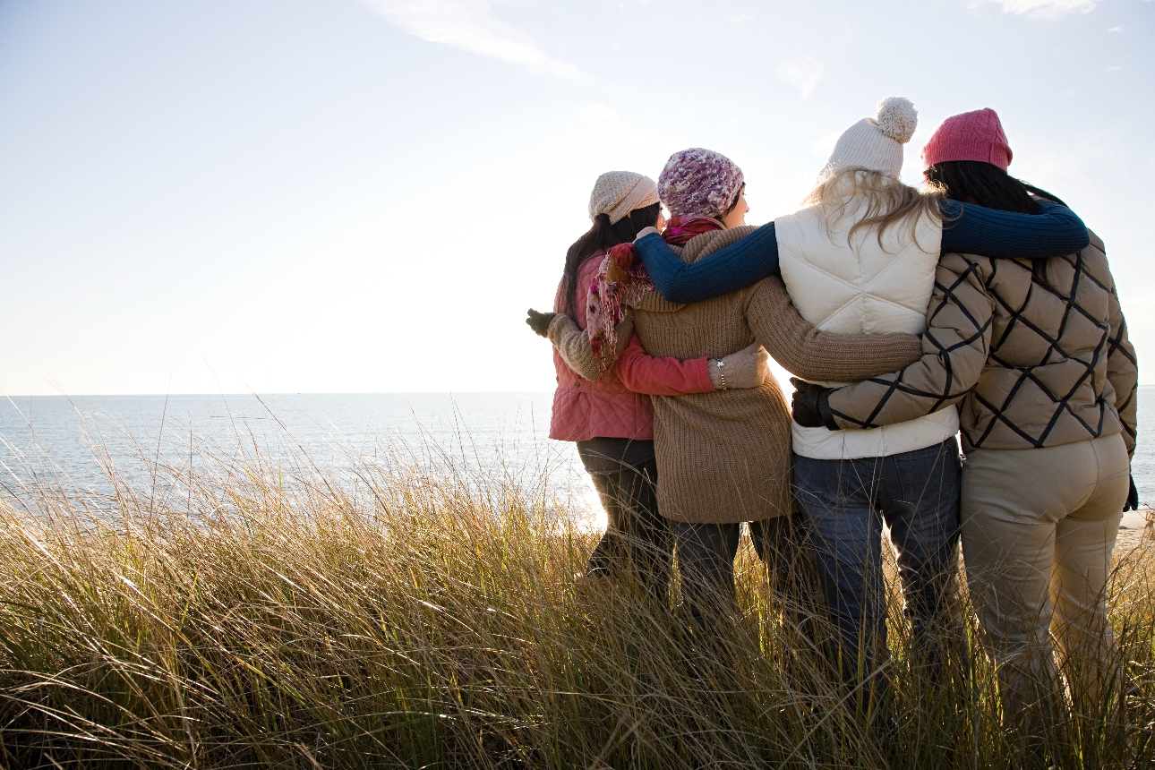 four people in outdoor clothes on a walk hugging