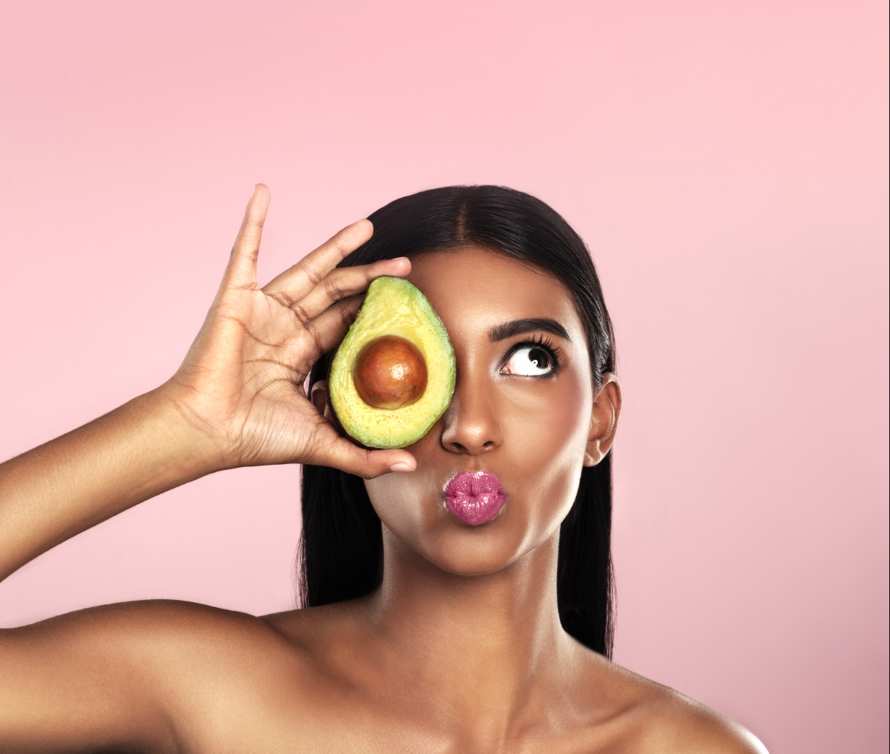 woman holding an avocado to her face