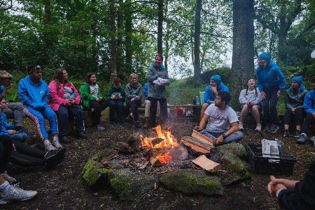 children and young adults sitting around a campfire