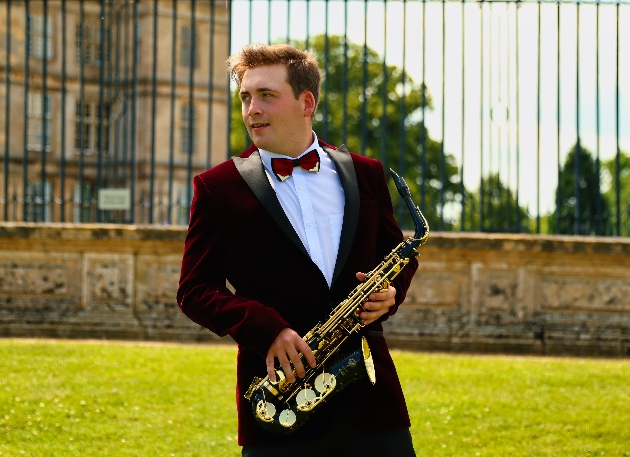 man in red velvet jacket playing saxophone