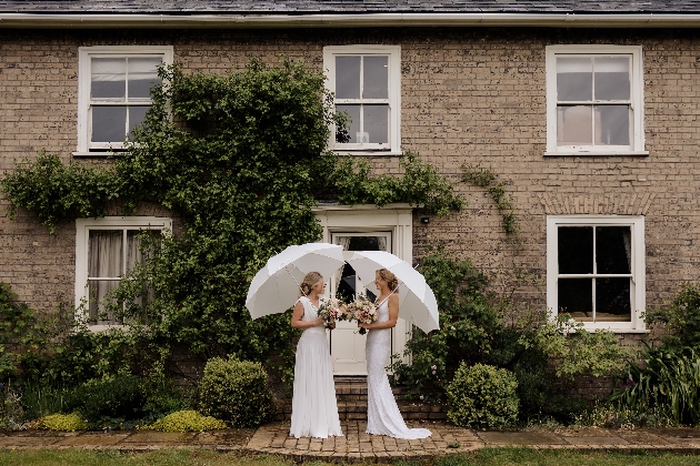 two brides under white umbrellas