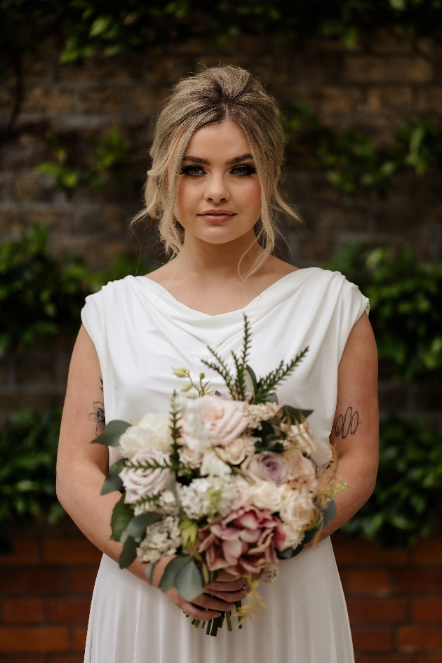 close up of lady wearing white plain bridal dress holding bouquet