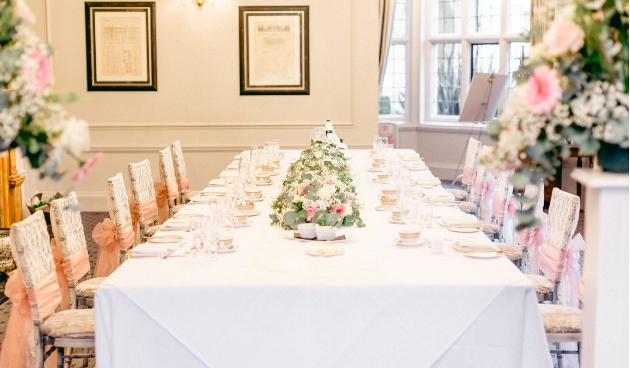 wedding table with white tablecloth and peach flowers