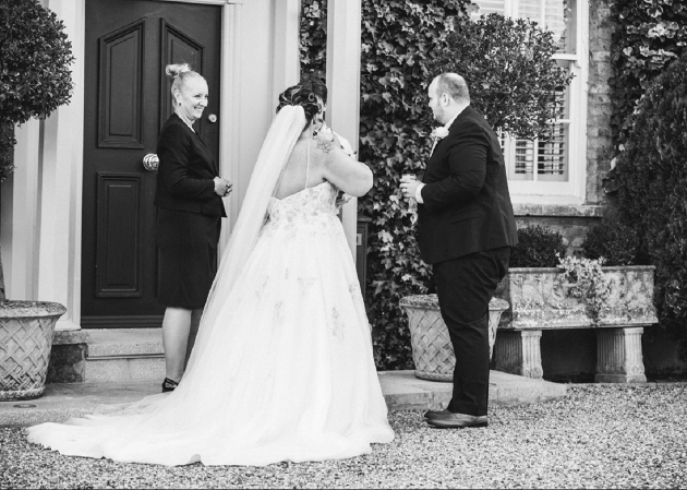 black and white image of a bride and groom outside their venue
