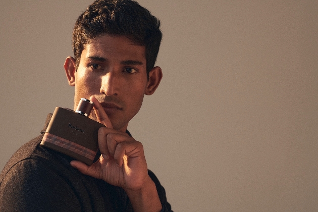 close up of man with dark hair holding Barbour fragrance bottle