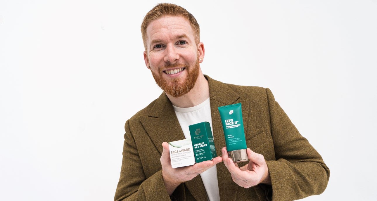 Neil Jones in tweed jacket holding products in his hands