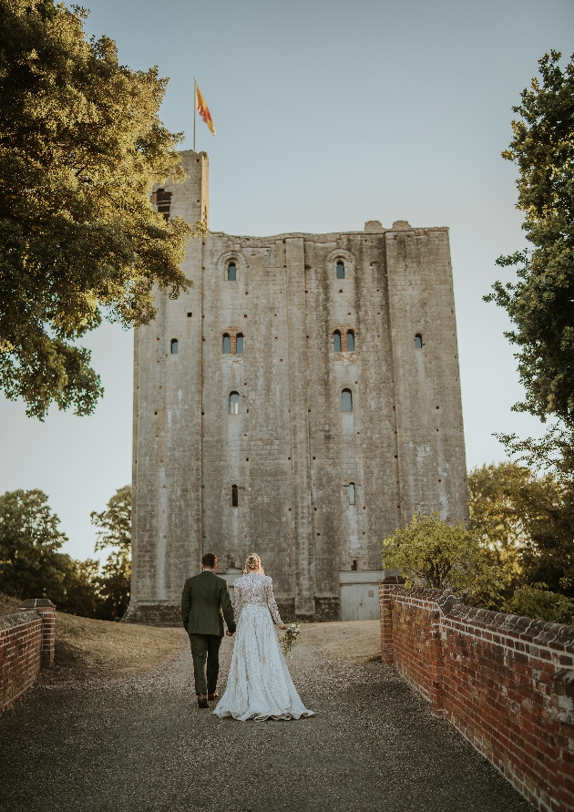 bride and groom walking up to Hedingham Castle