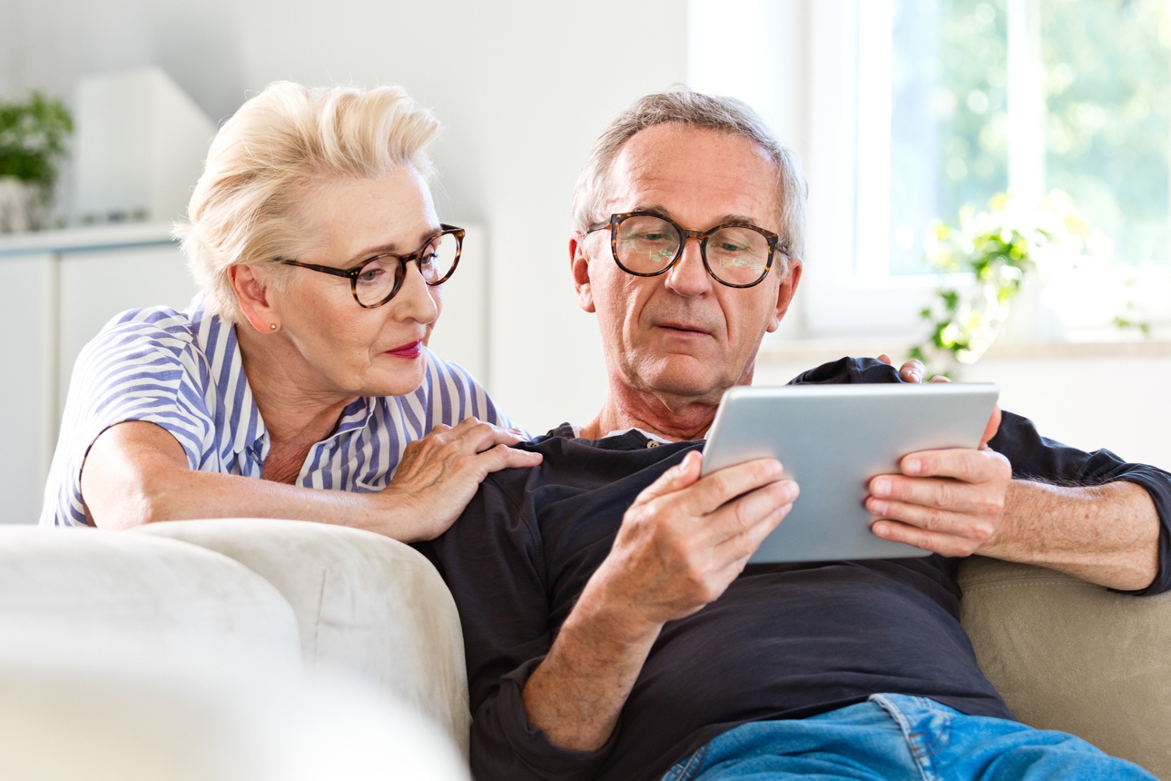 an older dad looking at an ipad on the sofa