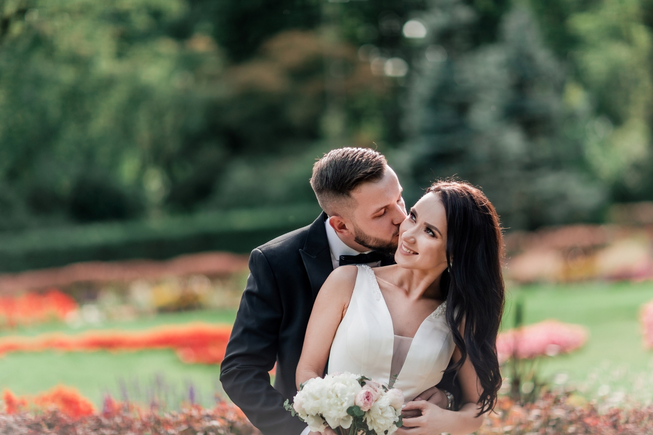 bride and groom in wedding attire cuddling in a garden