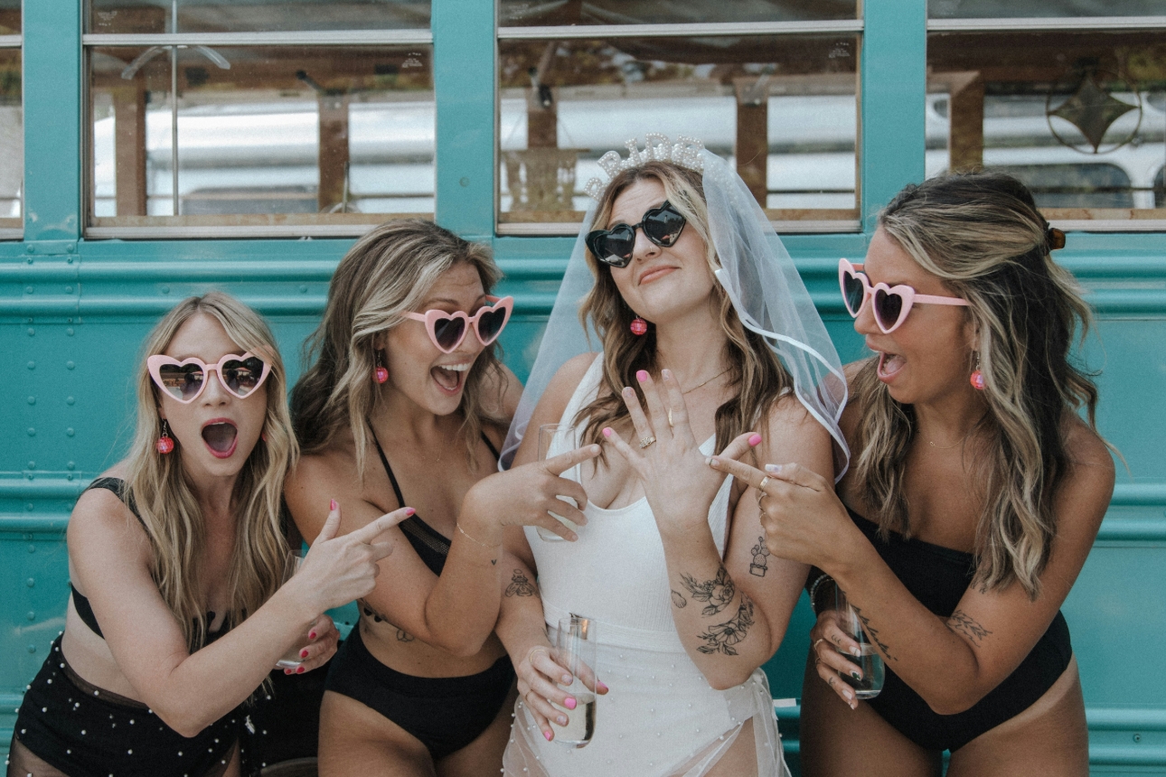 four women posing in front of blue bus