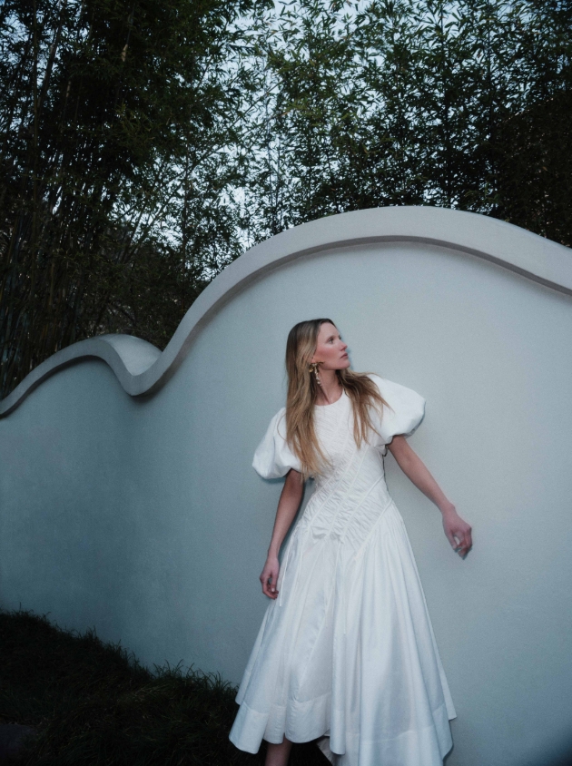 A midi dress with a shaped hemline, a crew neckline, and a ruched bodice, featuring fashionable puff sleeves