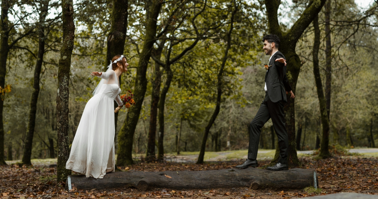 couple in wedding attire balancing on a log 